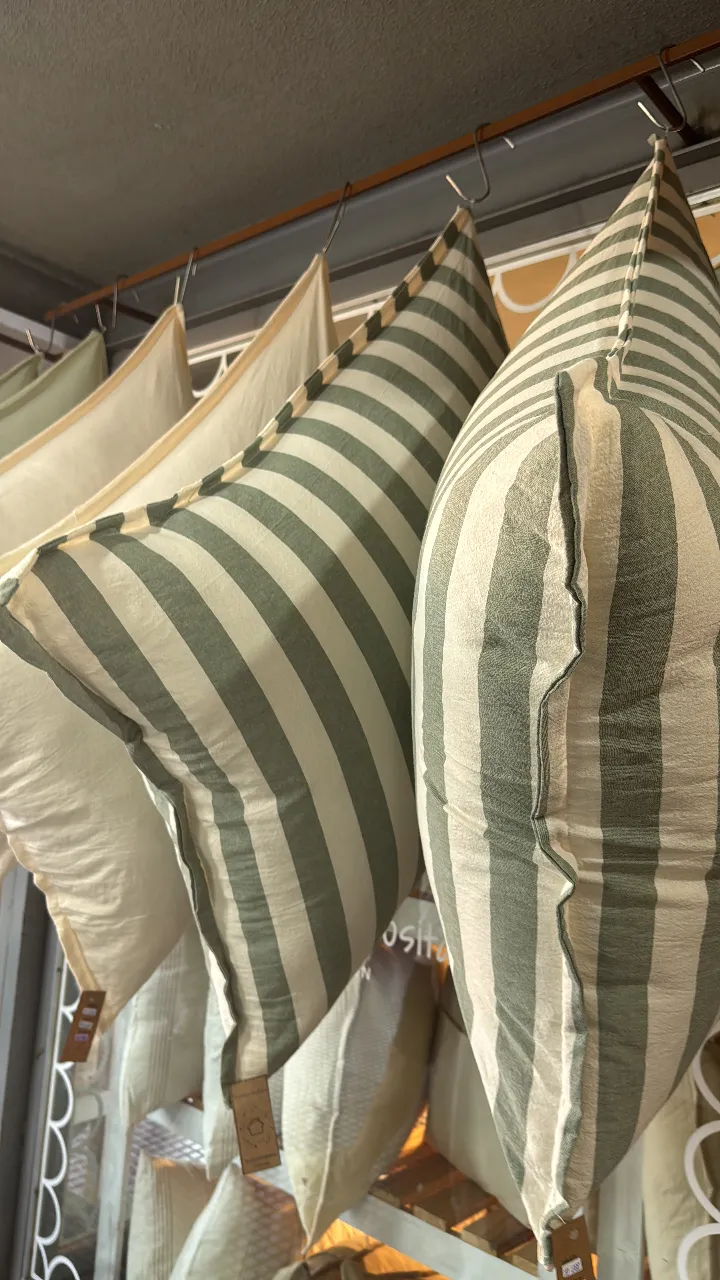 Almohadón de diseño a rayas verdes y crudo, ideal para darle un toque de estilo a tu living o dormitorio. Su diseño atemporal y los colores neutros lo hacen perfecto para combinar con cualquier decoración.