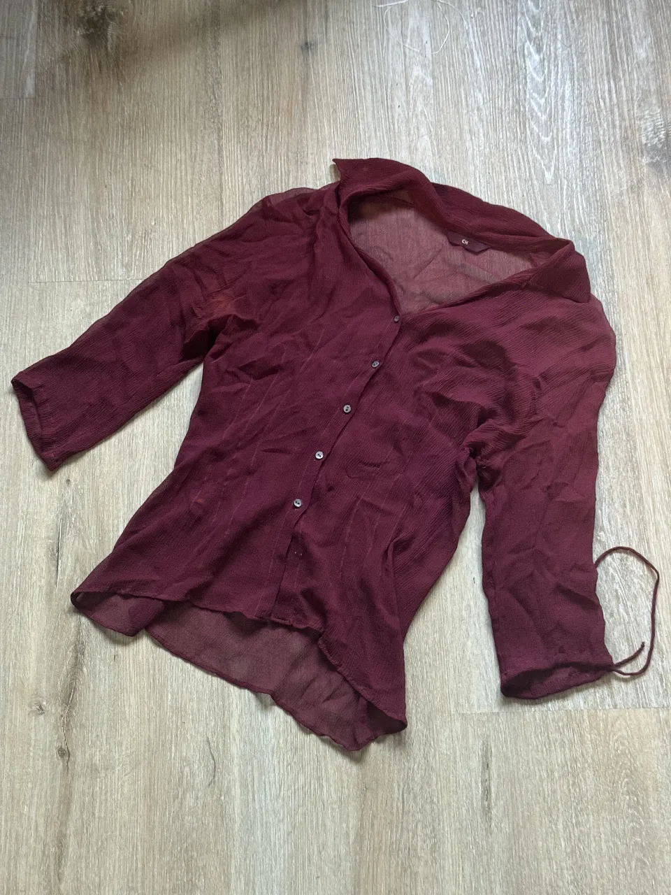 Camisa de seda color bordó, con mangas 3/4 y botones al frente. Ideal para un look elegante y sofisticado.