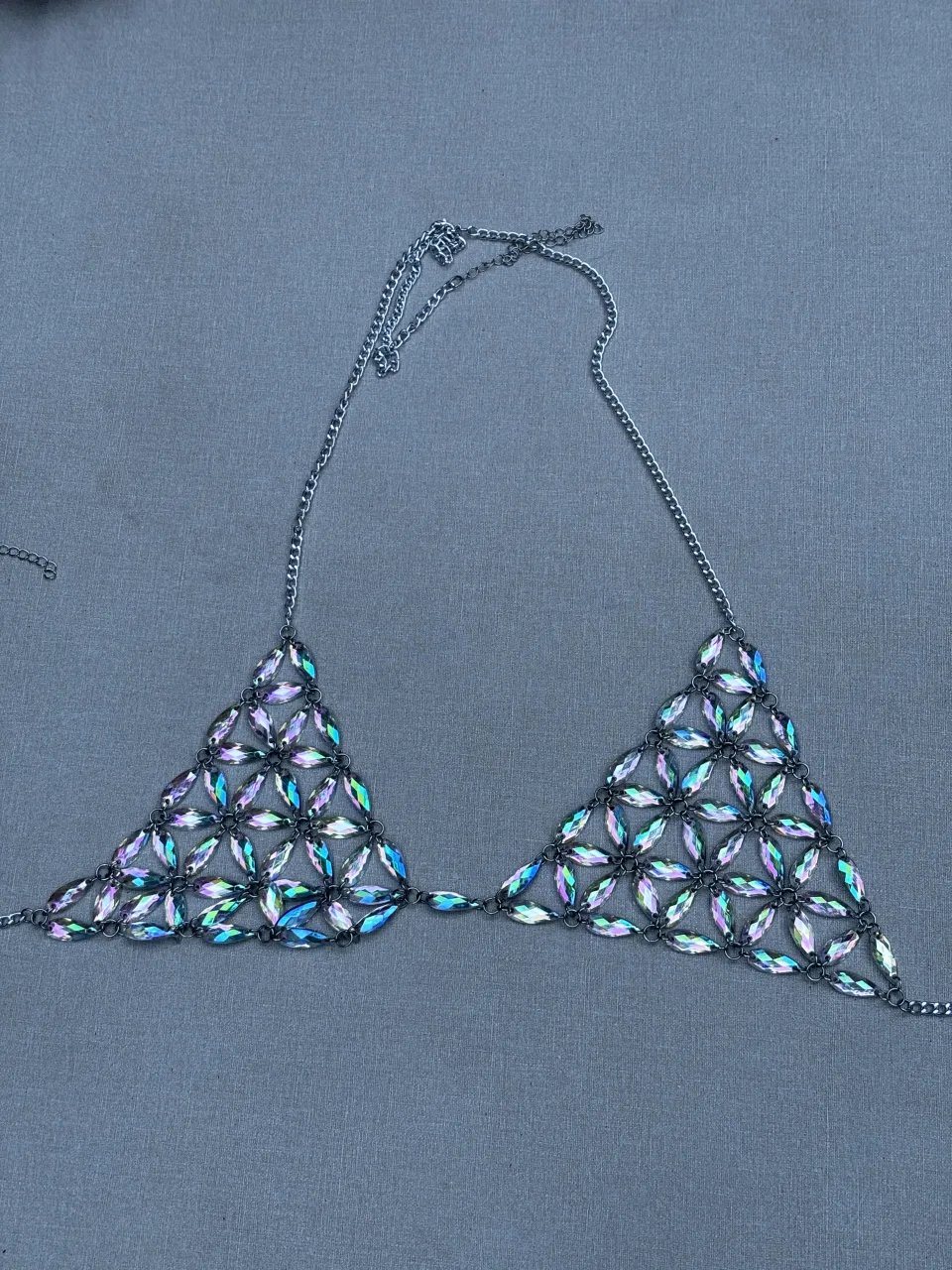 Collar tipo corpiño con cadenas plateadas y apliques de cristales facetados iridiscentes en forma de pétalos. Se abrocha en la nuca y en la espalda con cadenas.