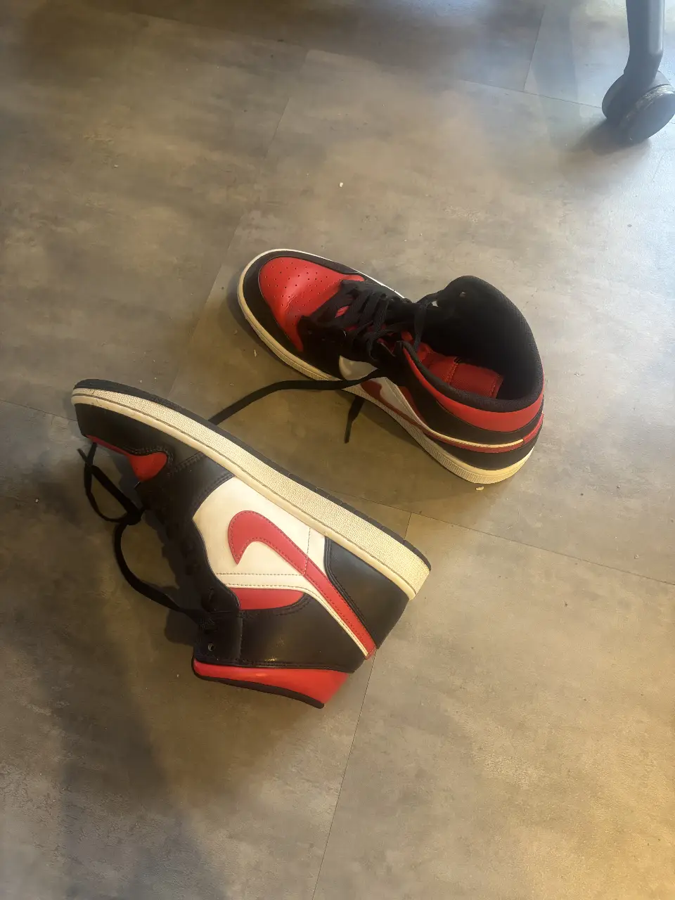 Zapatillas Air Jordan 1 Retro High OG, un clásico del calzado urbano. Combinación de cuero negro y rojo, con el icónico logo de Nike. Ideales para un look casual y con estilo.