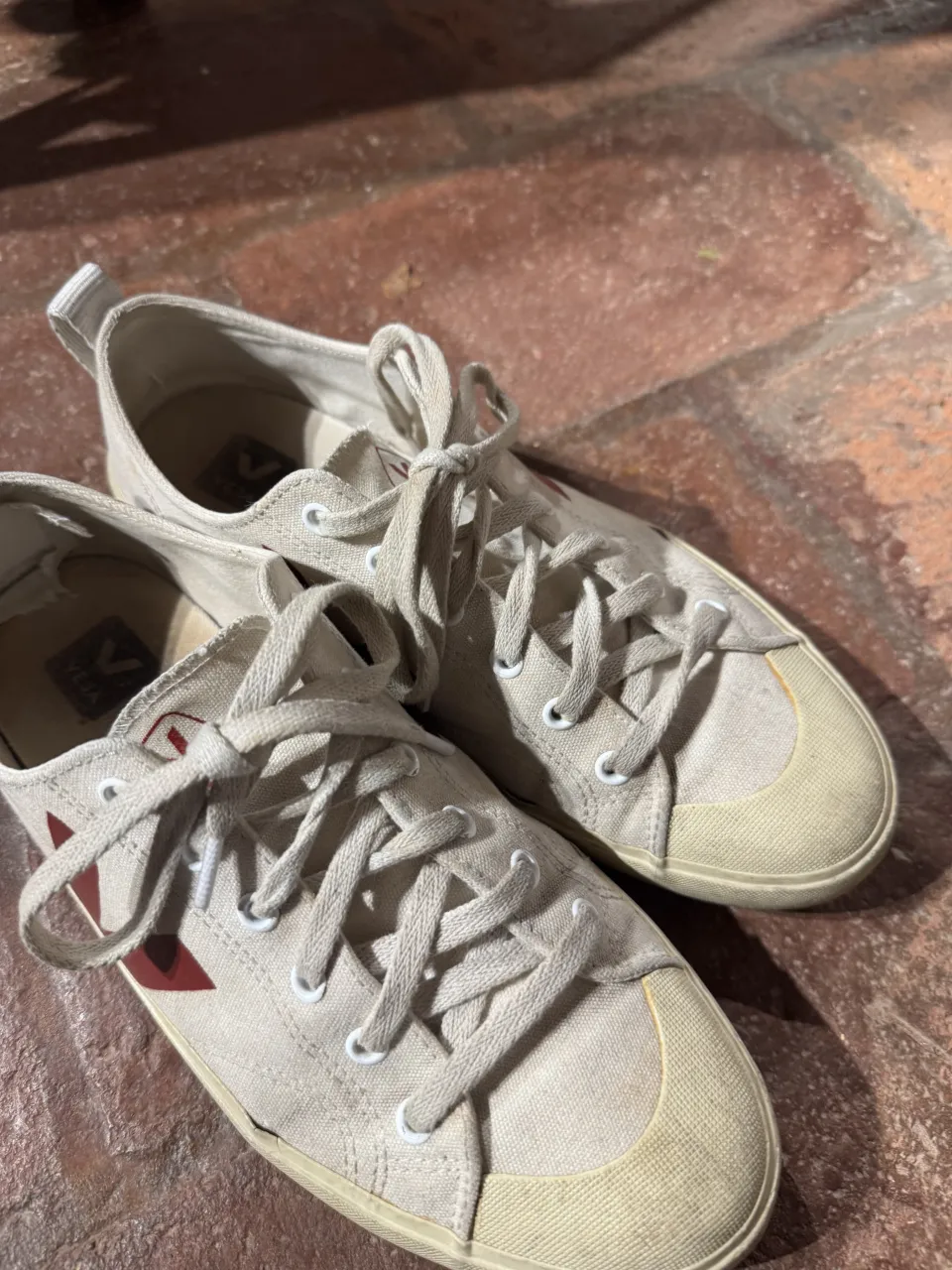 Zapatillas de lona color crudo con detalles en rojo. Cordones blancos.