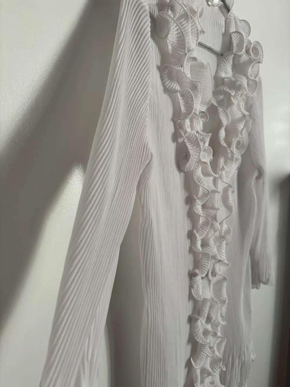 Blusa blanca con detalle de volados en el frente y mangas 3/4. Ideal para un look elegante y femenino.