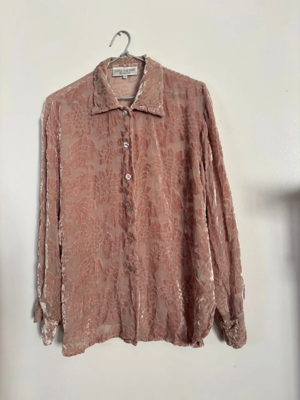 Blusa de terciopelo rosa con estampado floral, manga larga y botones. Ideal para un look vintage y elegante.